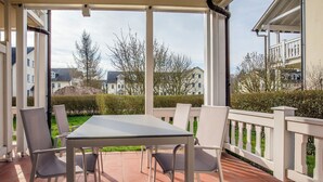 A covered patio with a table and chairs, overlooking a residential area. - Comfortplus vacation apartment with 1 bedroom and terrace on the first floor (Ostseebad Binz)