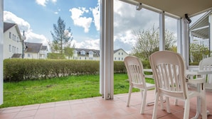 A covered patio area with a view of a green lawn and houses in the background. - Comfort apartment with 1 bedroom and terrace on the first floor (Ostseebad Binz)