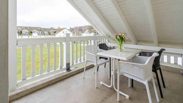 A covered patio with white railings, a table, and chairs. - Komfort Ferienwohnung mit 2 Schlafzimmern und Balkon im Dachgeschoss (Ostseebad Binz)