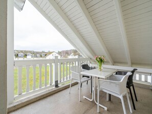 A covered patio with white railings, a table, and chairs.