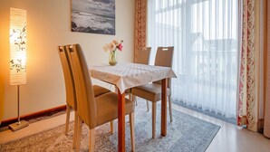A dining area with a table set for two, a vase with flowers, and a painting on the wall. - Komfort Ferienwohnung mit 2 Schlafzimmern und Balkon im Dachgeschoss (Ostseebad Binz)