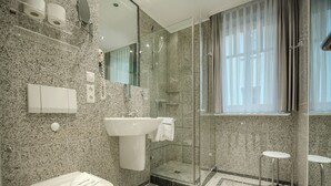 Une salle de bain moderne avec un comptoir en granit, un lavabo, des toilettes, une douche en verre et un petit tabouret.