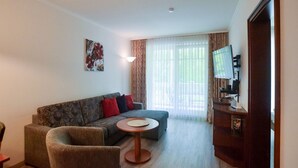 Uma sala de estar com sofá, poltrona, mesa de centro e televisão.