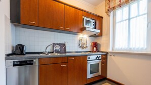 A kitchen with wooden cabinets, a microwave, a coffee maker, and a toaster. - Comfort apartment with 1 bedroom and balcony on the upper floor (Ostseebad Binz)
