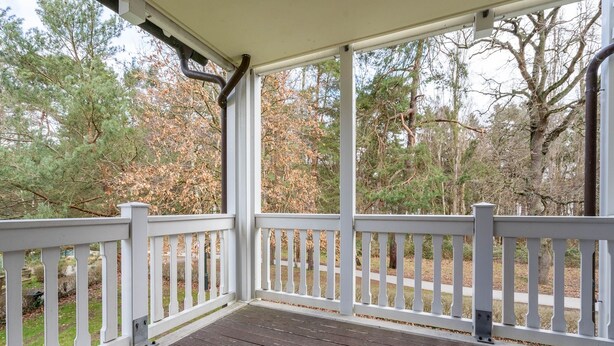 A covered porch with white railings and a wooden deck. - Comfort apartment with 1 bedroom and balcony on the upper floor (Ostseebad Binz)