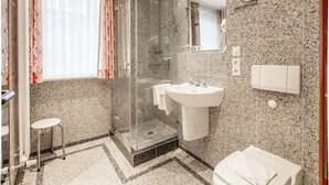 A modern bathroom with a glass shower enclosure, a white sink, and a toilet. - Comfort apartment with 1 bedroom and balcony on the upper floor (Ostseebad Binz)