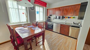Una cocina moderna con armarios de madera, electrodomésticos de acero inoxidable y una zona de comedor con mesa y sillas de madera.