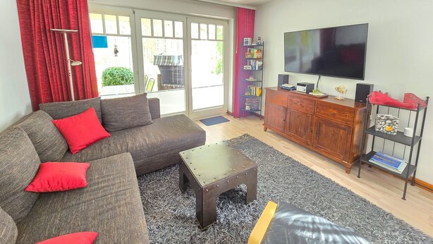 Una sala de estar con un sofá, una mesa de centro, un televisor y una estantería.