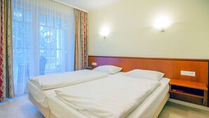 Una cama doble con cabecera de madera, una mesita de noche y un velador.