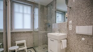 Un baño moderno con ducha de vidrio, un lavabo blanco y un inodoro.