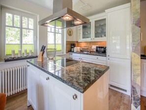 A modern kitchen with white cabinetry, a granite countertop, and a built-in stove.