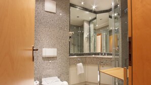 Ein modernes Badezimmer mit einer Granittheke, einer Duschkabine aus Glas und einem Holzwaschtisch.