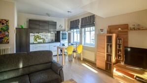 Ein modernes Wohnzimmer mit einer Couch, einem Fernseher und einem Essbereich mit Stühlen und einem Tisch.