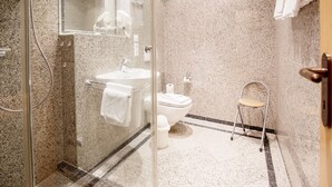 A modern bathroom with a glass-enclosed shower, a white sink, and a toilet.