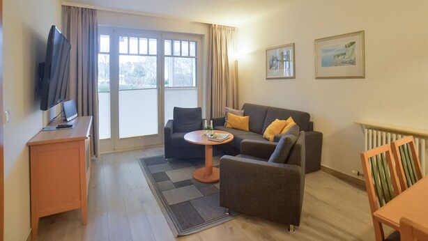 A modern living room with a sofa, armchairs, a coffee table, and a TV.