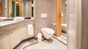 Et stilfuldt badeværelse med bordplade i granit, toilet og spejl.