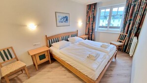 Et hotelværelse med en dobbeltseng, to sengeborde, en stol, et vindue med gardiner og en radiator.