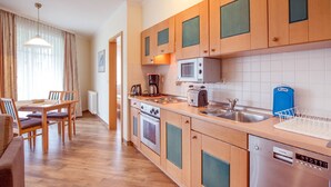 Una cucina moderna con mobili in legno, un lavello in acciaio inossidabile, un forno a microonde, una macchina da caffè e una lavastoviglie Siemens.
