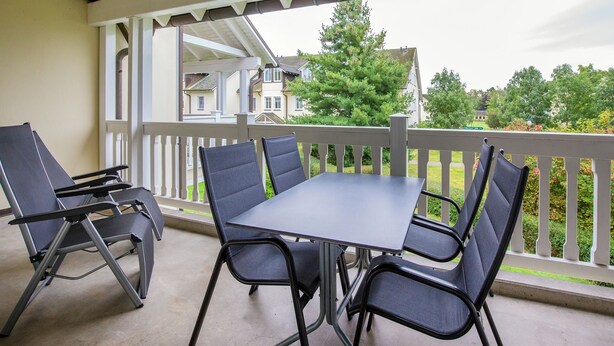 Une terrasse couverte avec une table et quatre chaises.