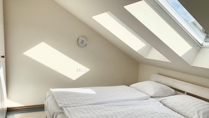 A bedroom with a skylight, a bed, and a wall-mounted light switch. - Comfort apartment with 2 bedrooms and balcony on the top floor (Ostseebad Binz)