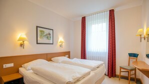 Une chambre d’hôtel avec deux lits, un bureau, une chaise et deux lampes fixées au mur.