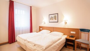 Ein Hotelzimmer mit einem großen Bett, einem Sessel, einem Nachttisch und einem Bild an der Wand.