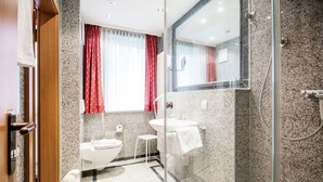 Ein modernes Badezimmer mit Duschkabine aus Glas, einem weißen Waschbecken und einer Toilette.