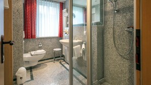 Ein modernes Badezimmer mit Duschkabine aus Glas, Waschbecken und Toilette.