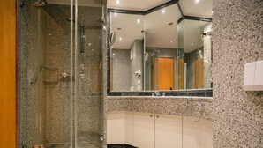 Een moderne badkamer met een douche met glazen wand, een grote spiegel en een wit toilet.
