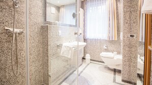 A modern bathroom with a glass-enclosed shower, a sink, and a toilet.