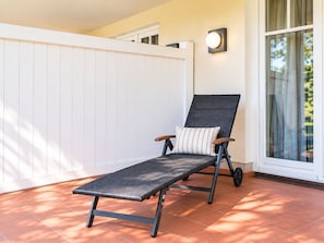 A sun lounger with wheels, a cushion, and a wall-mounted light fixture. - Komfortplus Vacation Apartment with 1 bedroom and a terrace on the first floor (Ostseebad Binz)