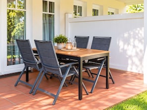 Une terrasse avec une table en bois et quatre chaises, une plante en pot et une bougie sur la table.