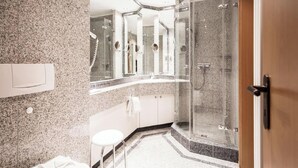 Ein modernes Badezimmer mit einer Granittheke, einer Duschkabine und einer weißen Toilette.