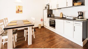 Eine moderne Küche mit weißen Schränken, einem Holztisch und einer Kaffeemaschine.