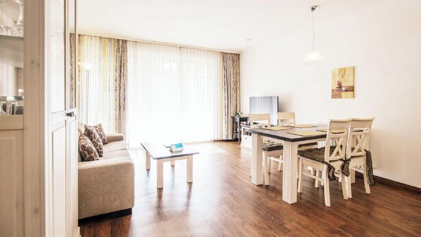 Ein geräumiges Wohnzimmer mit Holzboden, einer Couch, einem Couchtisch und einem Essbereich mit Tisch und Stühlen.