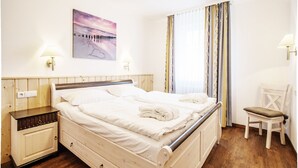 Ein Schlafzimmer mit einem hölzernen Bett, einem Nachttisch, einem Stuhl und einem Bild an der Wand.