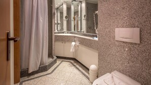 A modern bathroom with a shower, a toilet, a sink with a mirror, and a towel rack. - Classic apartment with 1 bedroom and terrace on the first floor (Ostseebad Binz)