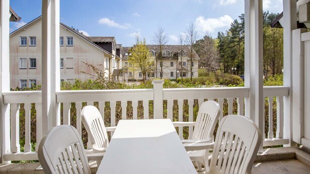 A covered outdoor area with a table and four chairs, overlooking a residential neighborhood.