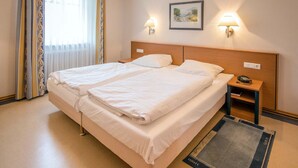 A hotel room with a double bed, two bedside tables, a nightstand, a lamp, and a framed picture on the wall.