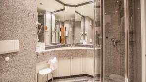 A modern bathroom with a granite countertop, a glass-enclosed shower, and a white toilet. - Comfort apartment with 1 bedroom and balcony on the top floor (Ostseebad Binz)
