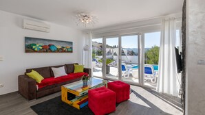 A modern living room with a brown sofa, red ottomans, and a colorful coffee table. - Last minute offers / Pet friendly / VERY low low season prices !!!! (Komarna)