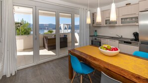 A modern kitchen with a large island, a dining area, and a view of the sea. - Last minute offers / Pet friendly / VERY low low season prices !!!! (Komarna)