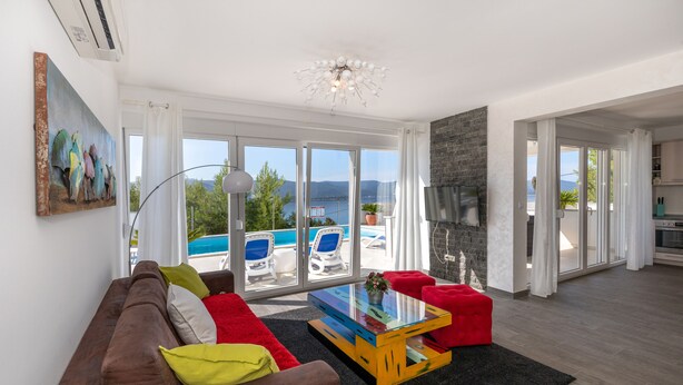 A modern living room with a sofa, a glass coffee table, and a view of a pool and mountains. - Last minute offers / Pet friendly / VERY low low season prices !!!! (Komarna)
