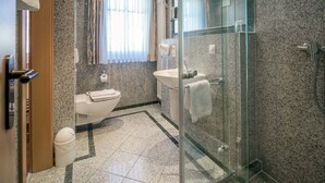 Un baño moderno con ducha envuelta en vidrio, inodoro y lavamanos.
