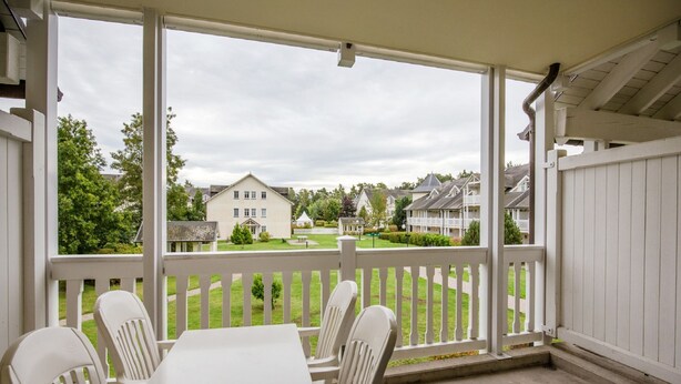 A covered patio with a white table and chairs, overlooking a well-maintained lawn and residential buildings. - Comfort apartment with 1 bedroom and balcony on the upper floor (Ostseebad Binz)
