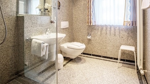 Un baño moderno con cabina de ducha de vidrio, un lavamanos blanco y un inodoro.