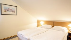 Una cama de matrimonio con dos almohadas y una mesita de noche con lámpara.