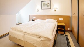 A hotel room with a bed, bedside table, lamp, and a framed picture on the wall. - Comfort apartment with 1 bedroom and balcony on the top floor (Ostseebad Binz)
