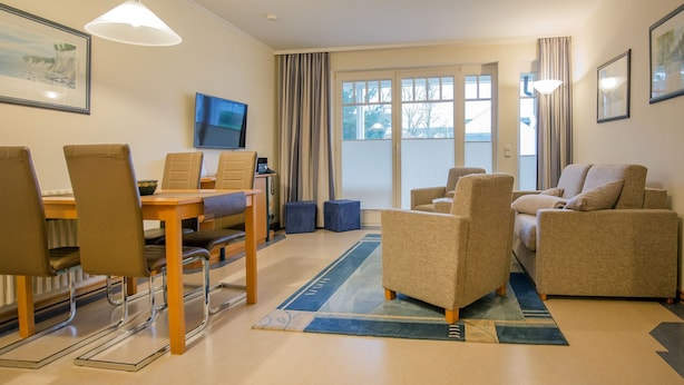 A modern hotel room with a dining area, a sofa set, and a television. - Comfort apartment with 1 bedroom and terrace on the first floor (Ostseebad Binz)