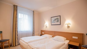 A hotel room with two beds, a large window with curtains, two bedside lamps, a framed picture on the wall, and a small bedside table with a book. - Comfort apartment with 1 bedroom and terrace on the first floor (Ostseebad Binz)